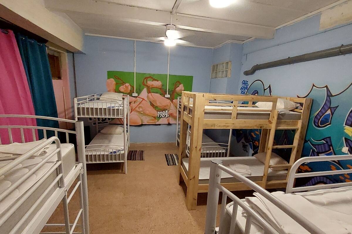 Un dormitorio con literas, un ventilador de techo y un mural en la pared.