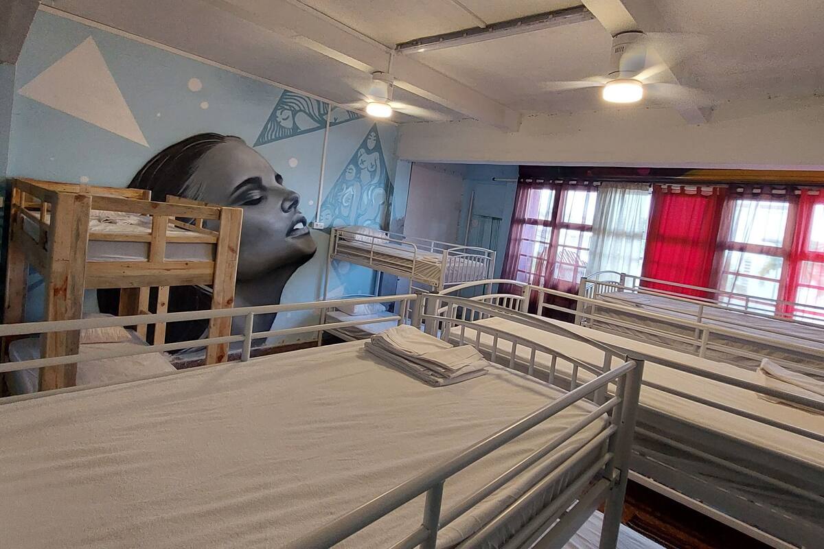Un dormitorio con literas, un ventilador de techo y un mural en la pared.