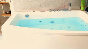 A white bathtub with a blue interior, a faucet, and a control knob. - Allegria Nimes (Nîmes)
