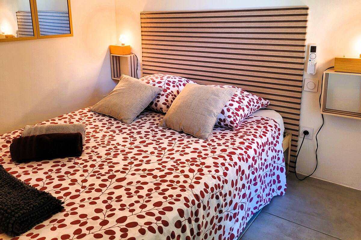 A neatly made bed with a patterned bedspread, two pillows, and a folded blanket.