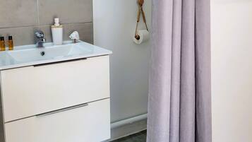 Une salle de bain avec un lavabo blanc, des articles de toilette, un miroir et un porte-serviettes.