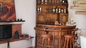 A bar area with wooden stools, a fireplace, and a collection of bottles on shelves. - Portion of a villa within walking distance of Mondello. (Palermo)