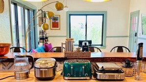 A kitchen with a wooden countertop, a kettle, a toaster, and a coffee maker.