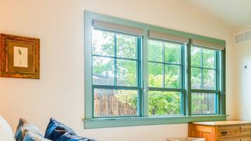 A bedroom with a bed, pillows, a dresser, and a window with a view of greenery.