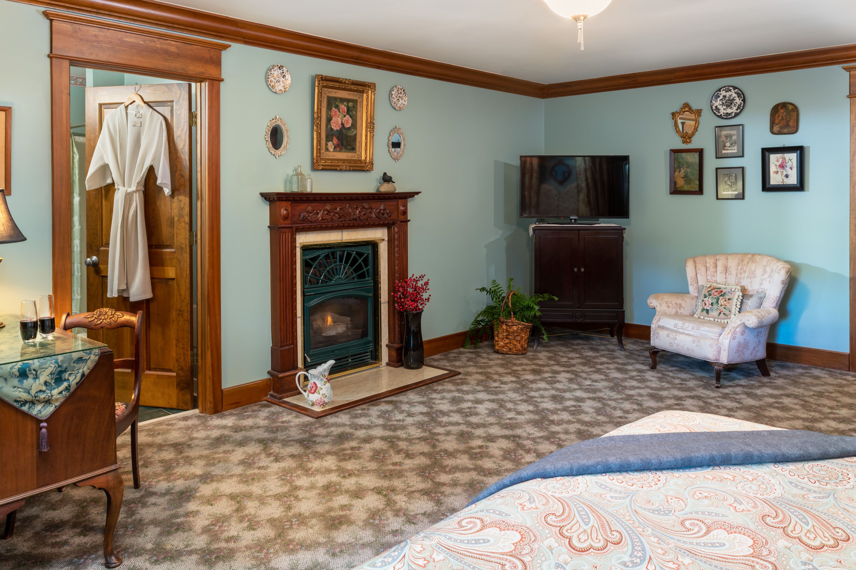 A room with a fireplace, a television, a chair, and a bed.