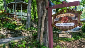 A gazebo, a stone wall, and a sign for 'Angel at Rose Hall Weddings' with a vacancy notice. - Angel At Rose Hall (Eureka Springs)