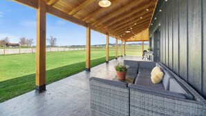 A covered outdoor seating area with a view of a grassy field. - La Bella Vita (The Beautiful Life) 5+ Bedrooms (Spearfish)
