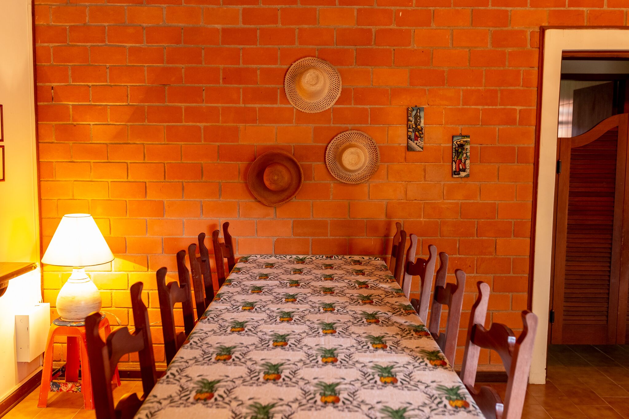 A dining area with a long table, chairs, and a brick wall.