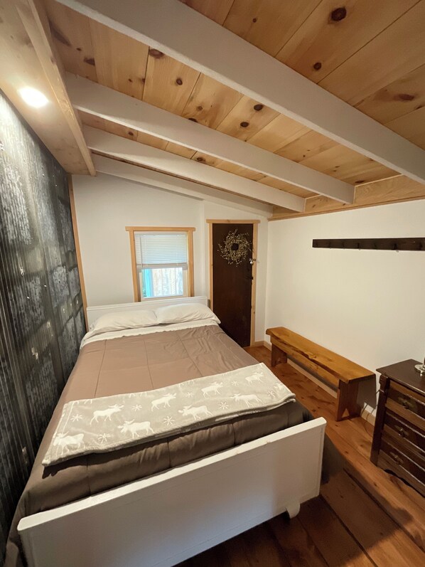 A bedroom with a bed, a bench, a dresser, and a door with a wreath. - Relax in peace along the Juniata River (Everett)