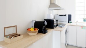 A modern kitchen with white cabinets, a wooden countertop, a coffee machine, a toaster, and a fruit bowl. - The Libournettes - Serenity (Libourne)