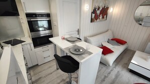 A modern kitchen with a built-in oven and a dining area with a white table and black chairs. - Le Petit Paradis. (Brive-la-Gaillarde)