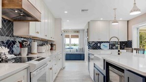 Una cocina moderna con armarios blancos, salpicadero blanco y negro y una isla central.