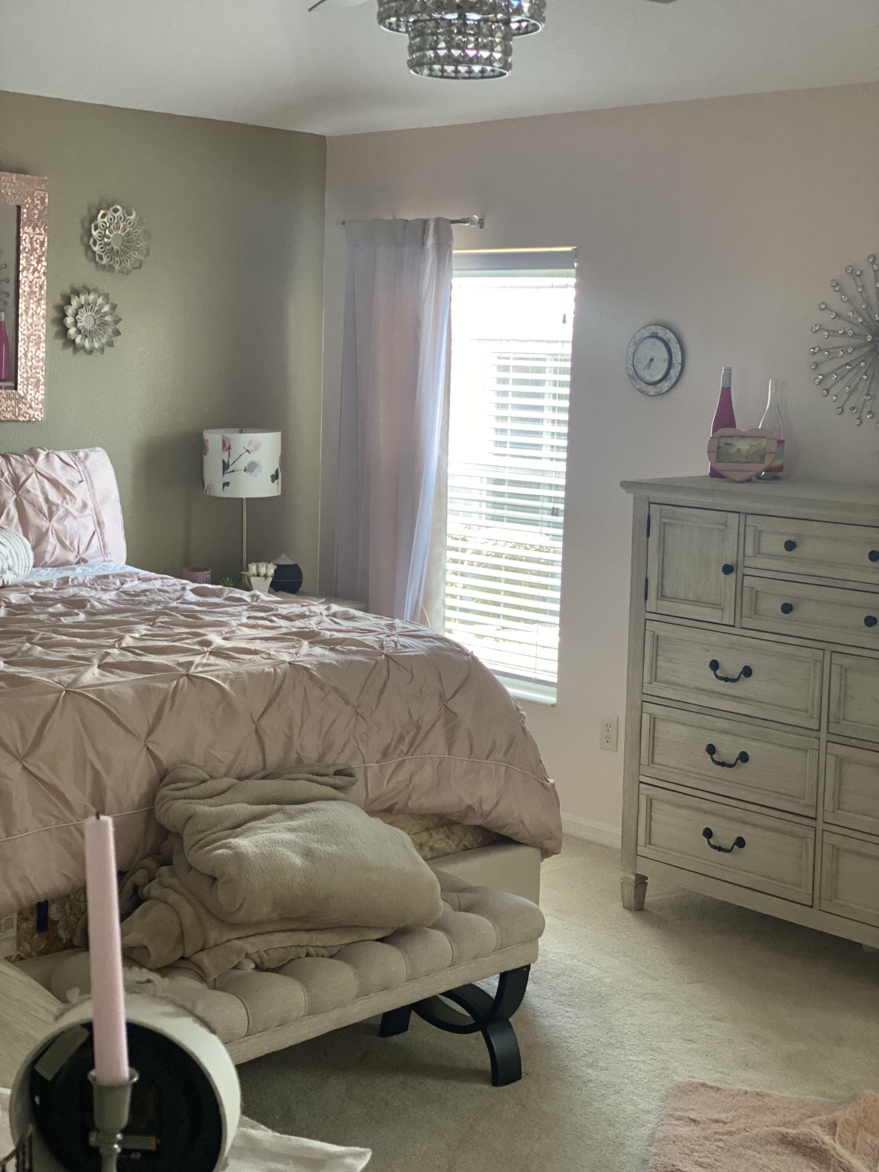 A bedroom with a bed, dresser, and a window with blinds.