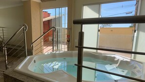 Un área de spa con un jacuzzi, encimeras de granito y una barandilla metálica.