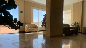 Un lobby espacioso con piso de baldosas brillantes, dos sofás y un ventanal que proporciona luz natural.