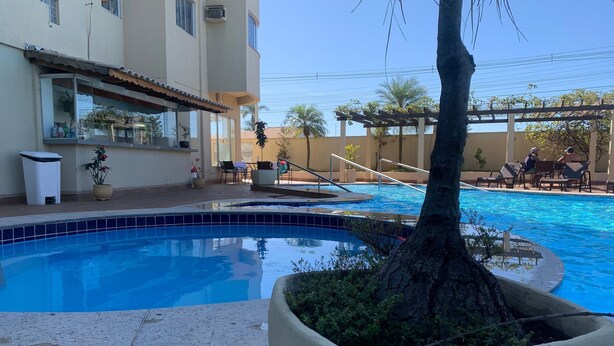 Una piscina con borde de azulejos, rodeada de sillas de descanso y una pérgola.