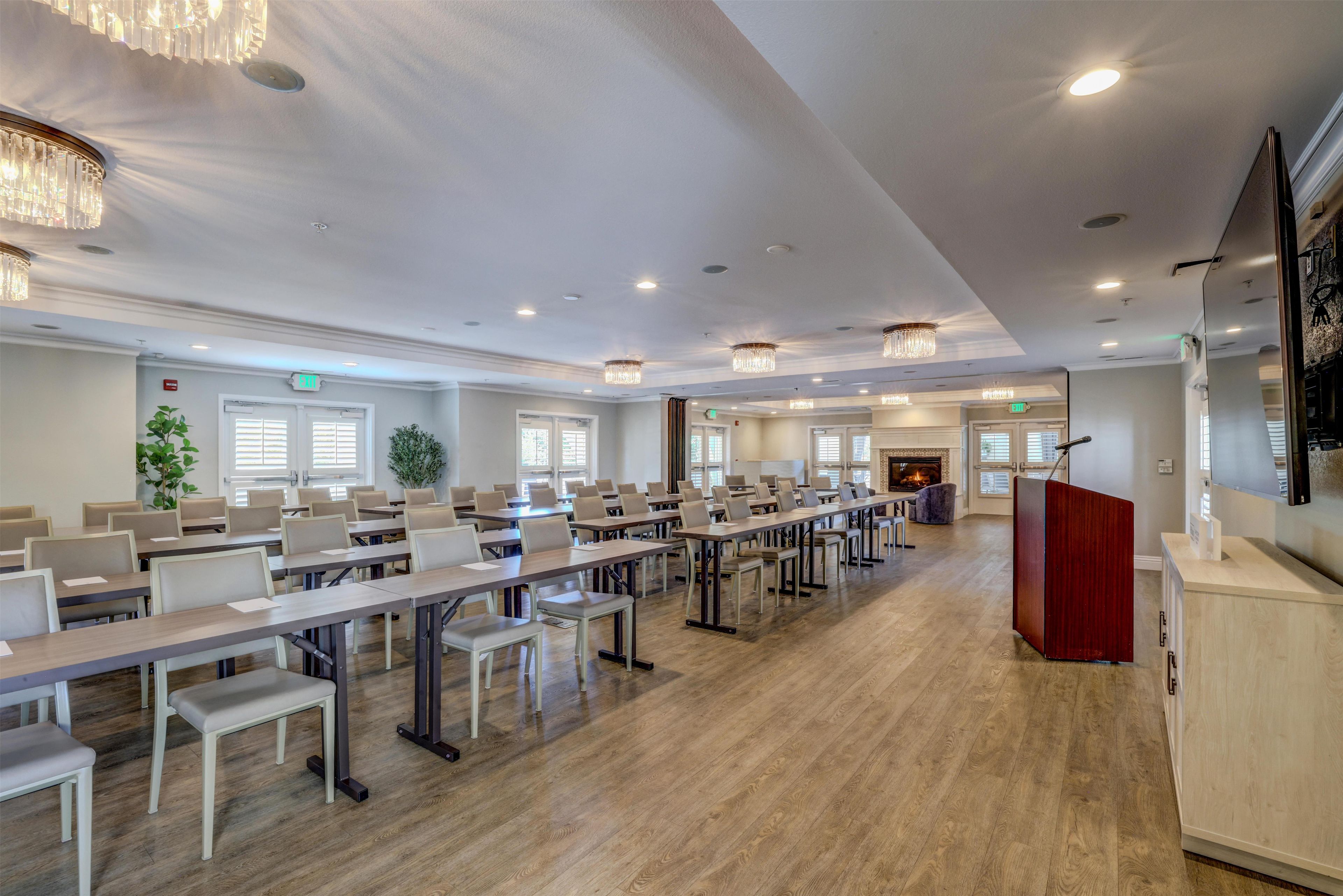 A conference room with multiple tables and chairs, a fireplace, and a large screen.