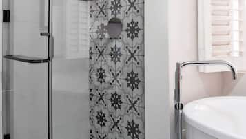 Eine Dusche mit Glastür, eine weiße Badewanne und eine Wand mit Muster.