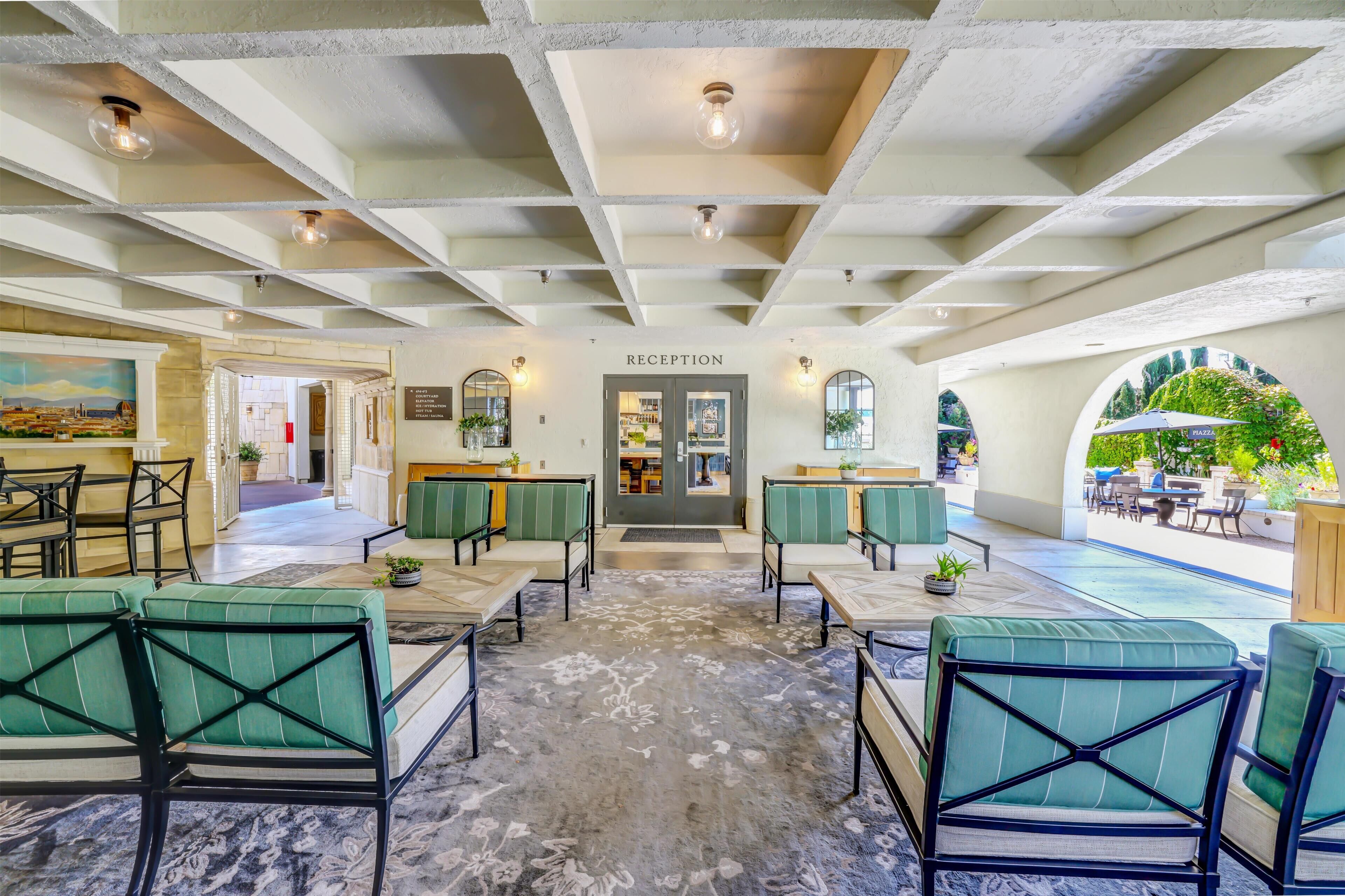 A reception area with a marble floor, green cushioned seating, and a ceiling with exposed beams.