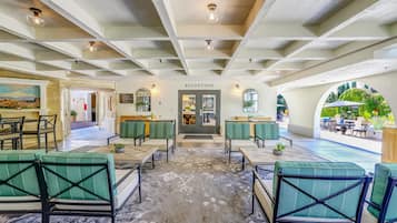 A hotel lobby with a reception desk, seating area, and a view of the outdoor patio.