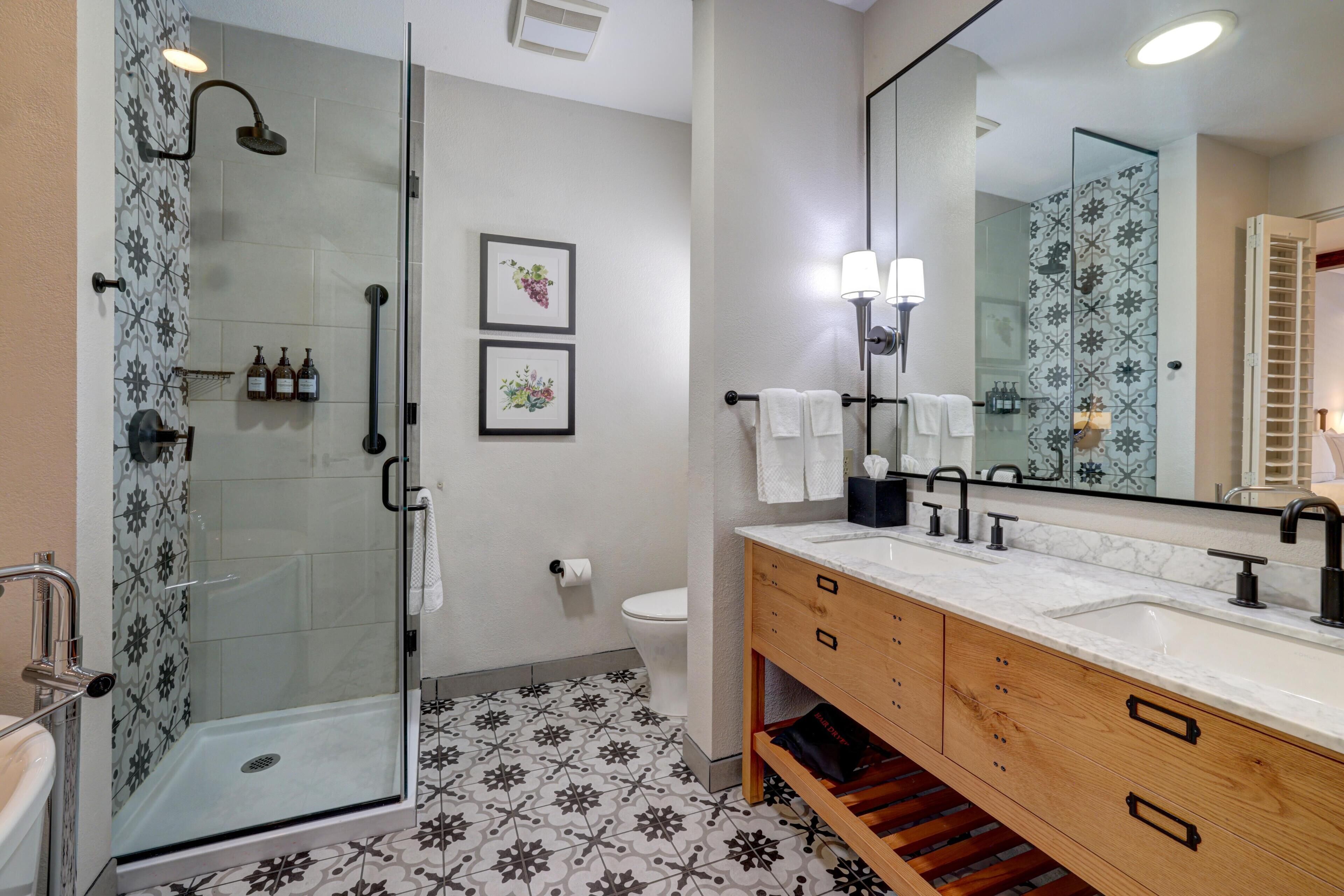 Un baño con ducha, inodoro, lavabo y un espejo grande.