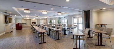 A spacious conference room with long tables and chairs, a podium, and a large window.