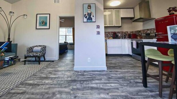 A spacious living area with a modern kitchen, a dining area, and a hallway leading to another room.