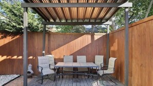 An outdoor patio with a wooden deck, a metal table, and six chairs.