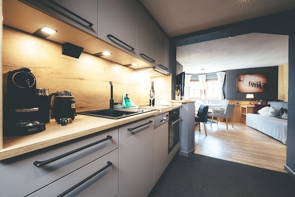 A modern kitchen with a wooden countertop, built-in appliances, and a dining area with a sofa and table.