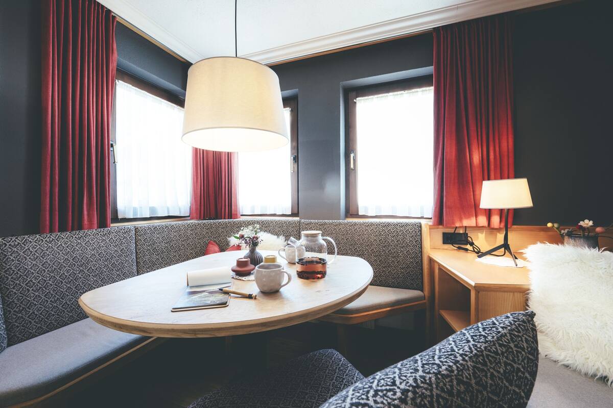A cozy room with a round table, a sofa, and a lamp.
