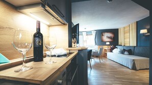 A modern hotel room with a wooden bar area, a sofa, and a bed. - Lärchenhof - Premium Apartments & Zimmer (Sankt Anton am Arlberg)