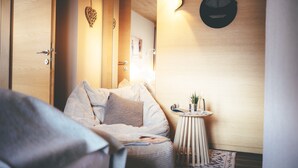 A cozy bedroom with a bed, bedside table, and a wall-mounted clock. - Lärchenhof - Premium Apartments & Zimmer (Sankt Anton am Arlberg)