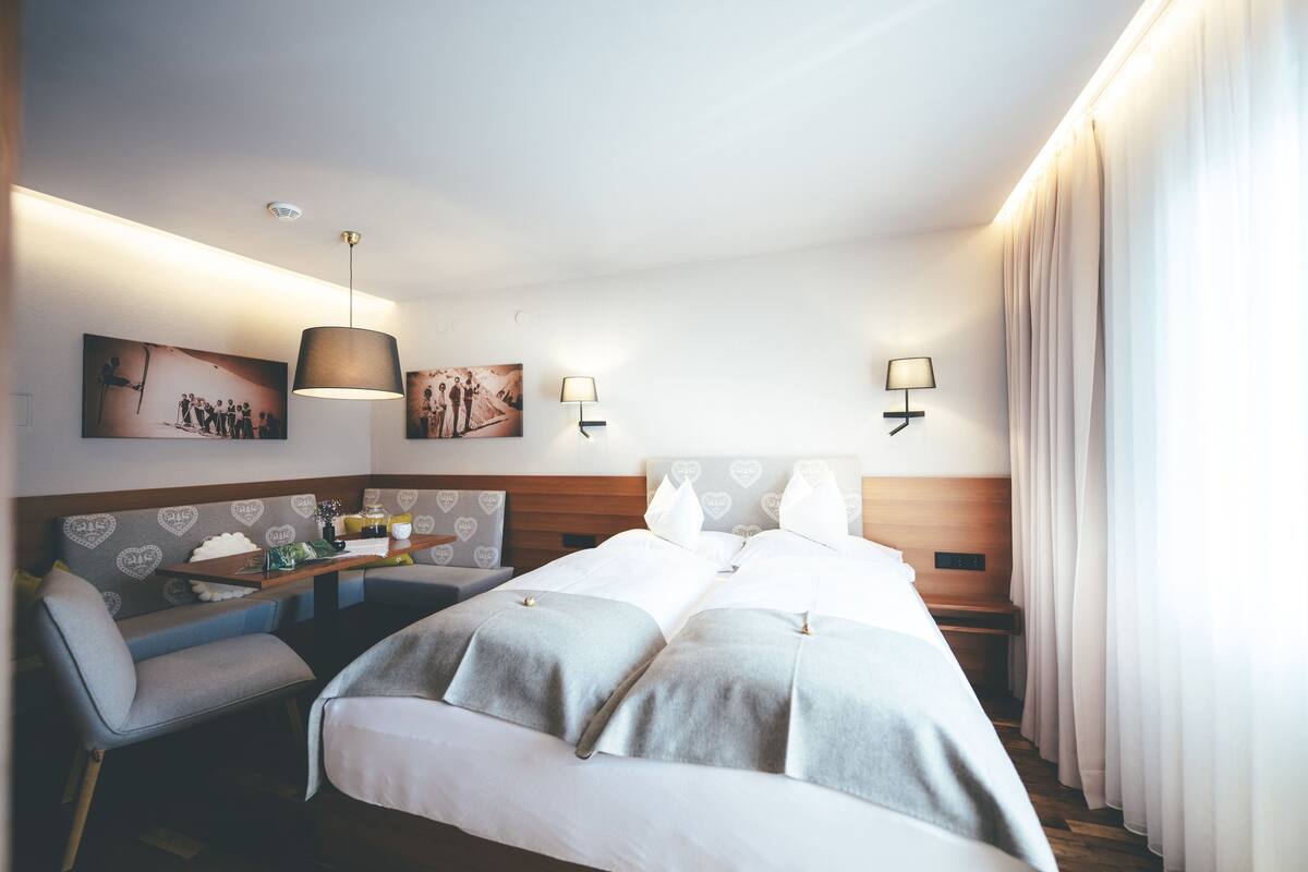 A hotel room with a large bed, a seating area with a table, and wall-mounted lamps.