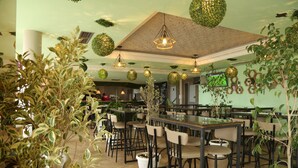 Un restaurante con un techo alto, decoraciones esféricas colgantes y numerosas mesas y sillas.