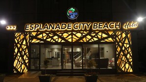 Exterior del Hotel Esplanade City Beach, con un diseño moderno, que presenta un letrero llamativo y una entrada de vidrio.