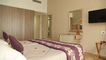Habitación de hotel con una cama grande, un armario de madera, un tocador con espejo y un televisor fijado a la pared.