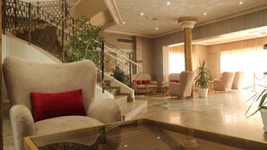Un amplio salón con un sillón grande, una mesa de centro de cristal y una escalera con barandilla de metal.