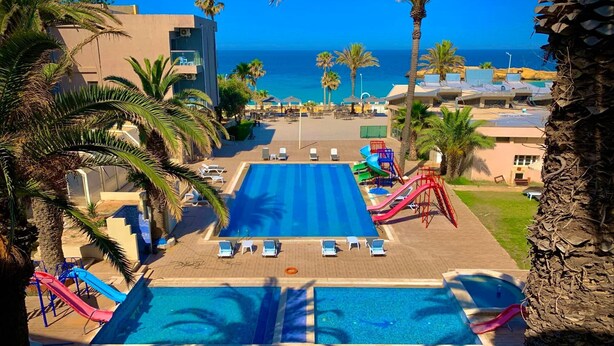 Un resort con una piscina grande, varias toboganes y vista al océano.