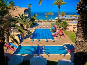 Un resort con una piscina grande, varias toboganes y vista al océano.