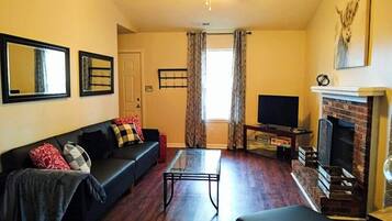 A living room with a sofa, a coffee table, a fireplace, and a television.