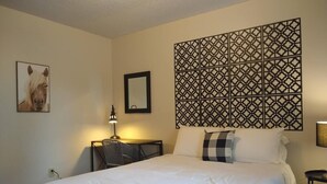 Habitación de hotel con una cama grande, un panel decorativo en la pared, un cuadro enmarcado y una mesita de noche con lámpara.