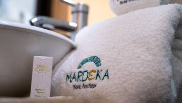 Un bagno con un lavandino, un berretto da doccia e due asciugamani con il logo 'Mardeka'.