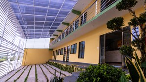 Un edificio con una zona esterna coperta, una facciata gialla e un balcone con ringhiere.