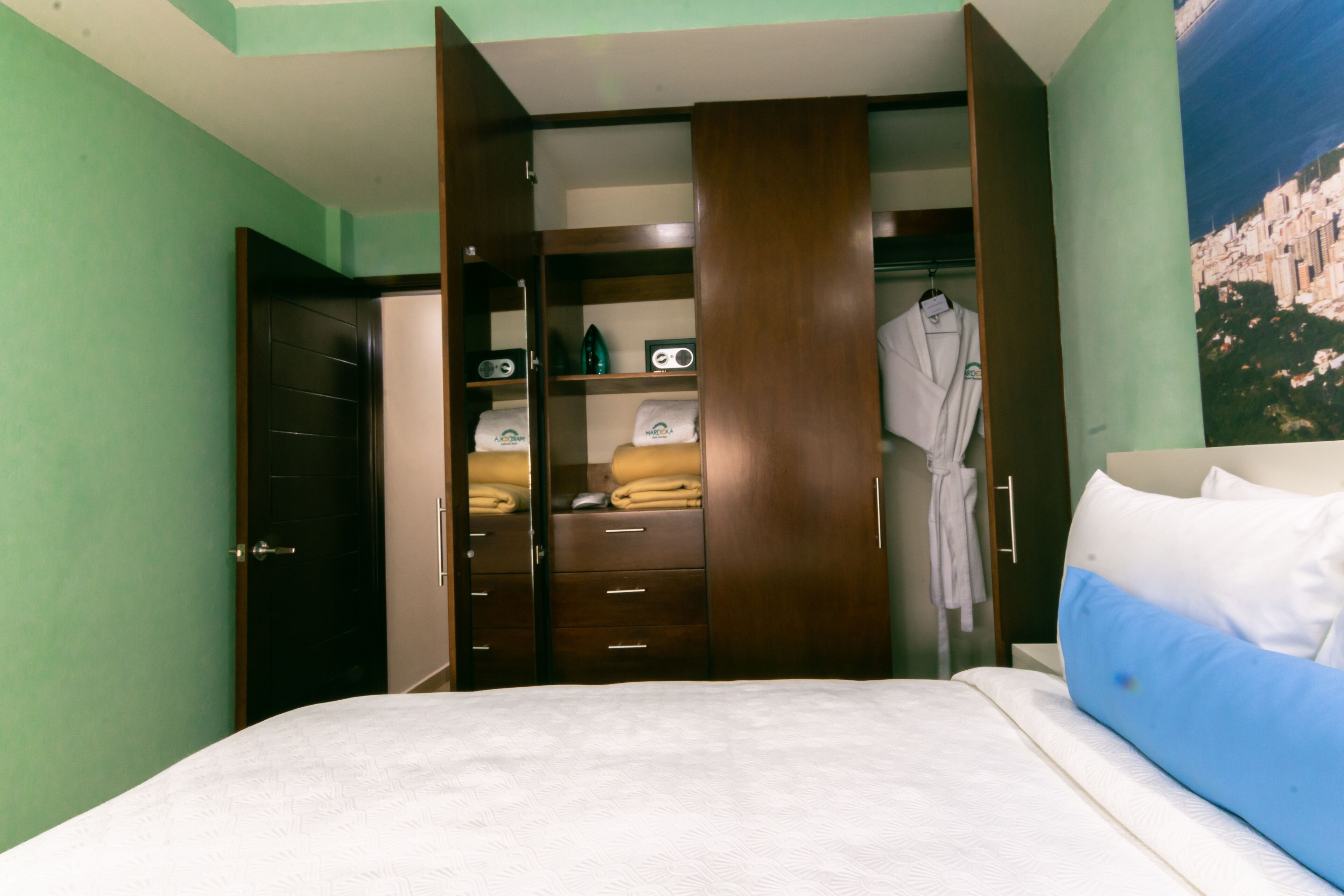 Un dormitorio con cama, armario con varios compartimentos y un cuadro en la pared.