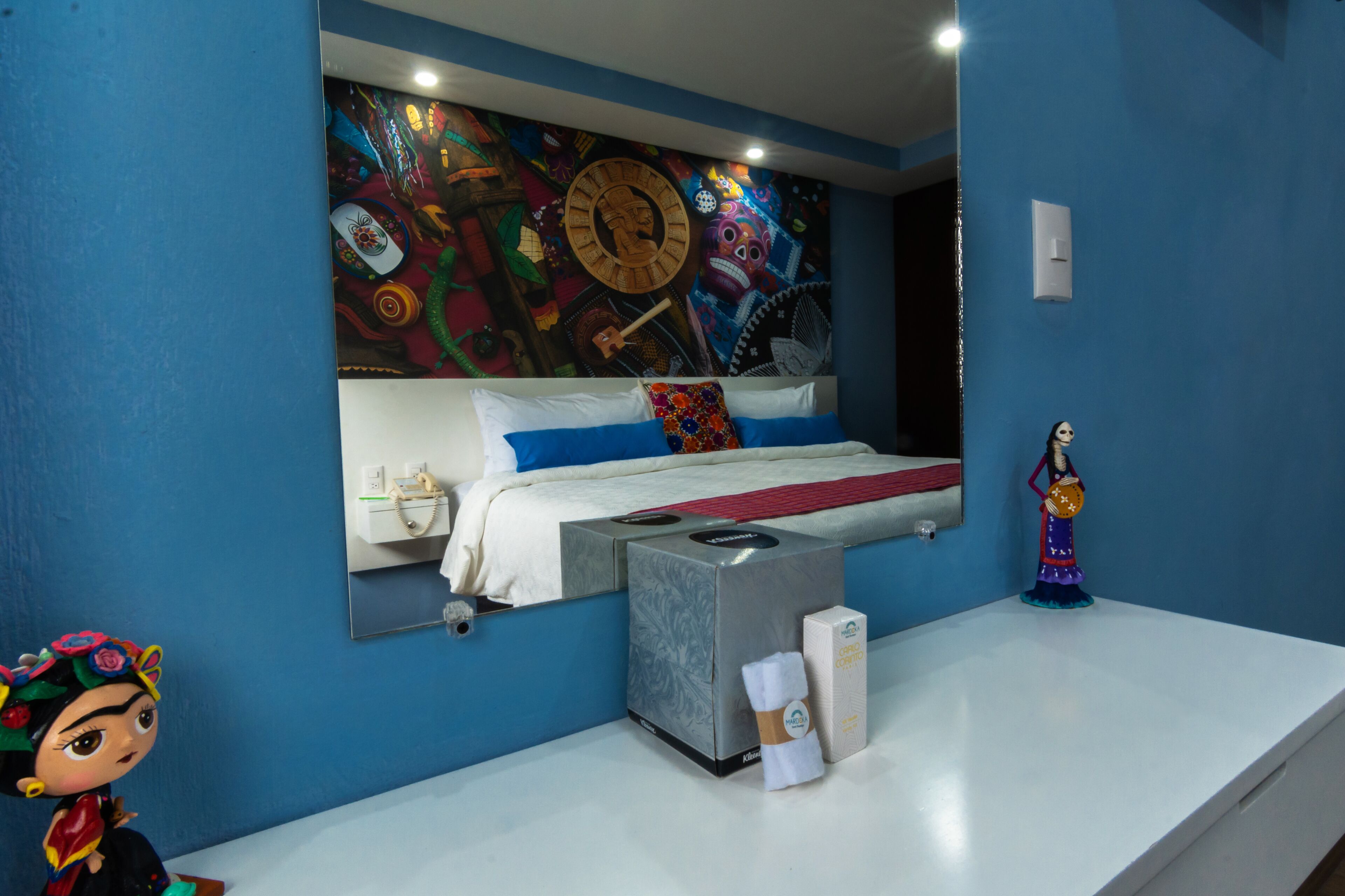 A bedroom with a large bed, a nightstand, a wall clock, and a decorative figure.