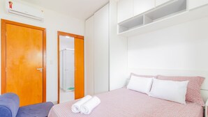 Een hotelkamer met een bed, een houten deur, een kledingkast en een spiegel.