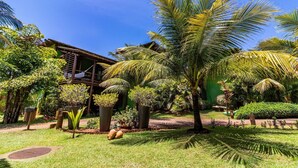 Um jardim exuberante com palmeiras, uma estrutura de madeira e um edifício verde.