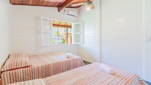 A room with two beds, wooden ceiling beams, a window with an open shutter, and an air conditioning unit. - GB69 Excellent 4/4 house 400m from the beach (Camaçari)