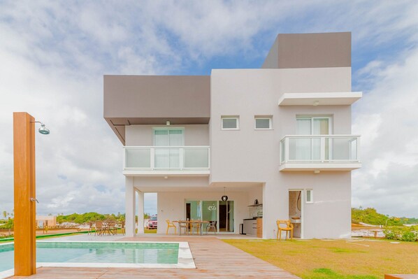 Una casa moderna de dos pisos con piscina, mobiliario exterior y vistas al paisaje circundante.
