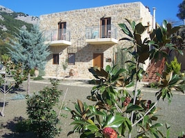 A stone building with two balconies, a staircase, and a sign that reads "Hotel".